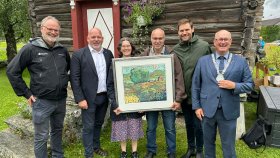 Oppstilling foran brunt stabbur. Knut Flatvad og Rita Dyrnes Flatvad, Østigard Flatvad i Sunndal, Møre og Romsdal mottok den nasjonale kulturlandskapsprisen i 2025 for arbeidet med å ta vare på verdier i jordbrukets kulturlandskap i Sunndal.