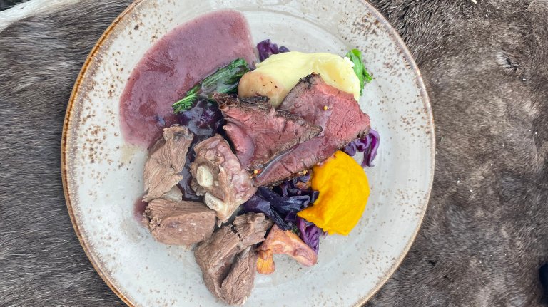 Bilde viser en tallerken med reinkjøtt middag.